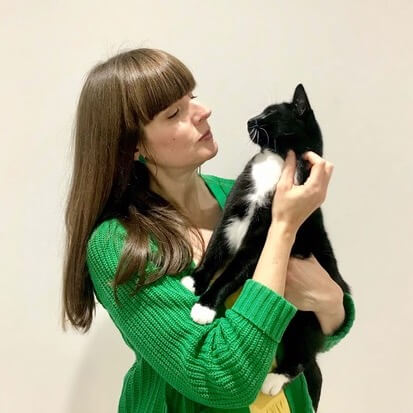 Megan holding her black and white cat, sharing a testimonial for Moira Fuller’s Business Mentoring