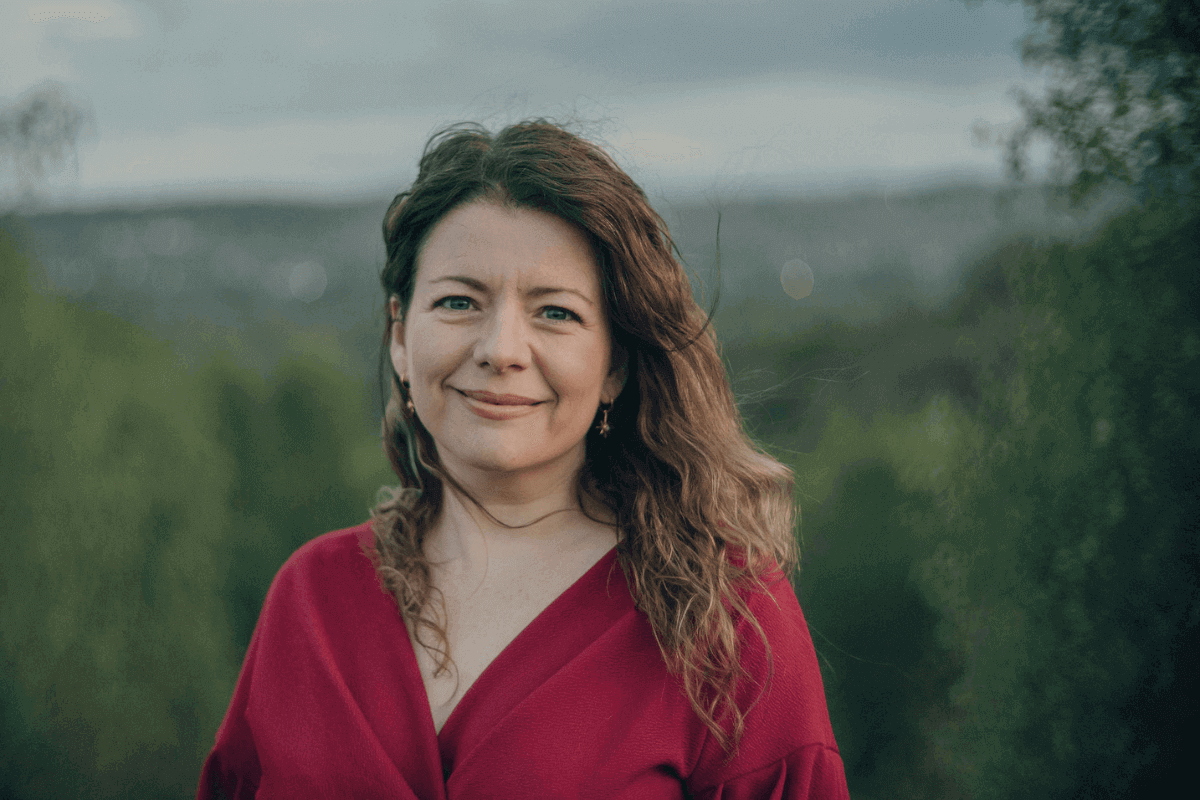 Moira Fuller, Business Mentoring expert, smiling outdoors in red top