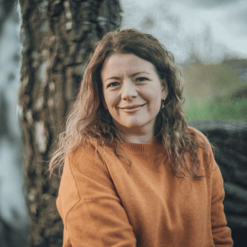 Moira Fuller, Business Mentoring expert, smiling outdoors in orange jumper