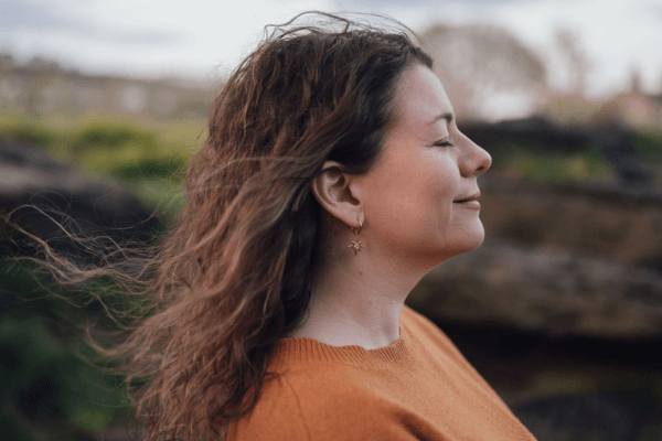 Moira Fuller, Business Strategist in the UK, standing outdoors eyes closed with peaceful expression