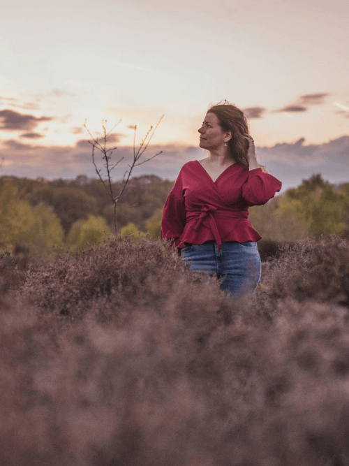 woman writing in a notebook wearing a soft pink jumper